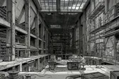 A dark factory converted to a library, with books on the shelves and a computer terminal in the center.